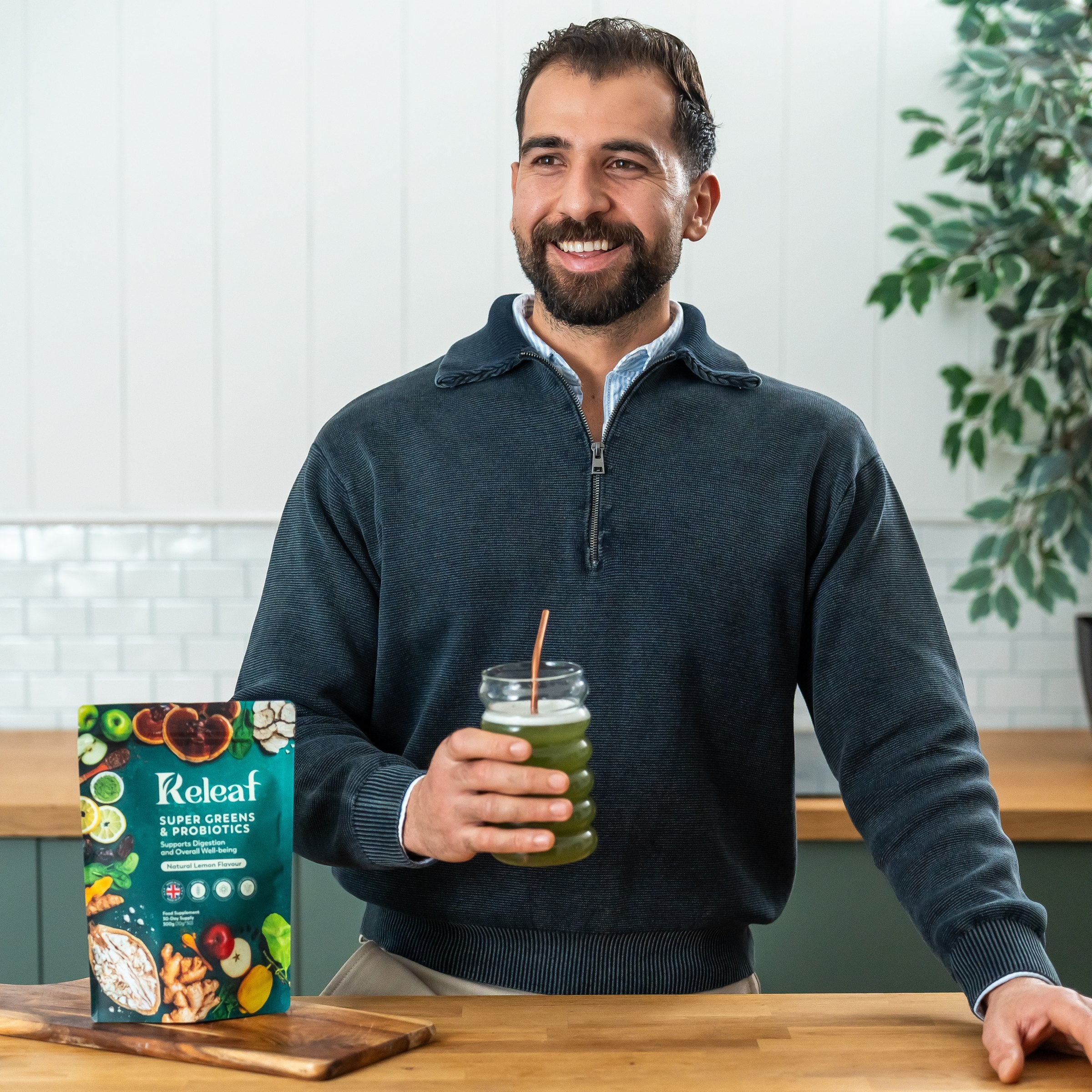 Releaf founder holding a glass of greens beside the Super Greens pouch