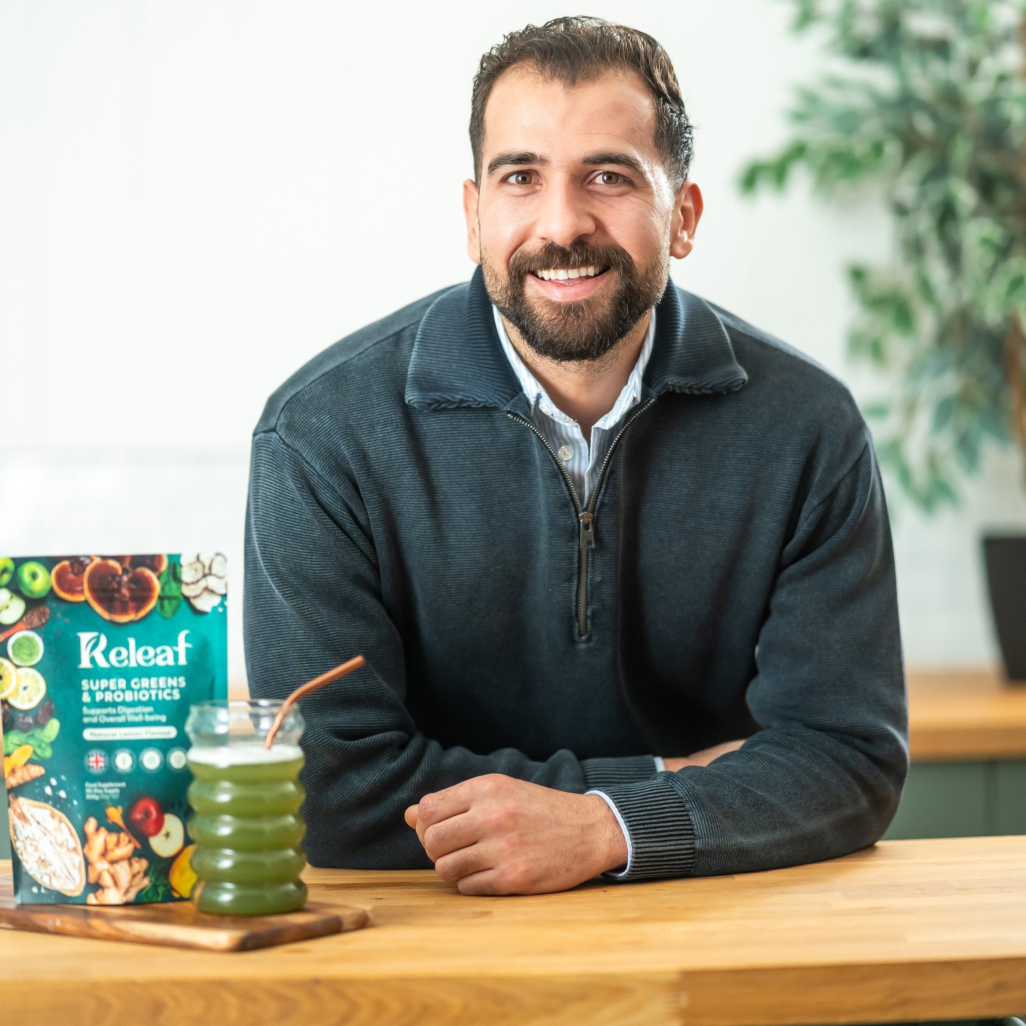 Releaf founder at the kitchen counter with the Super Greens pouch and a fresh green drink