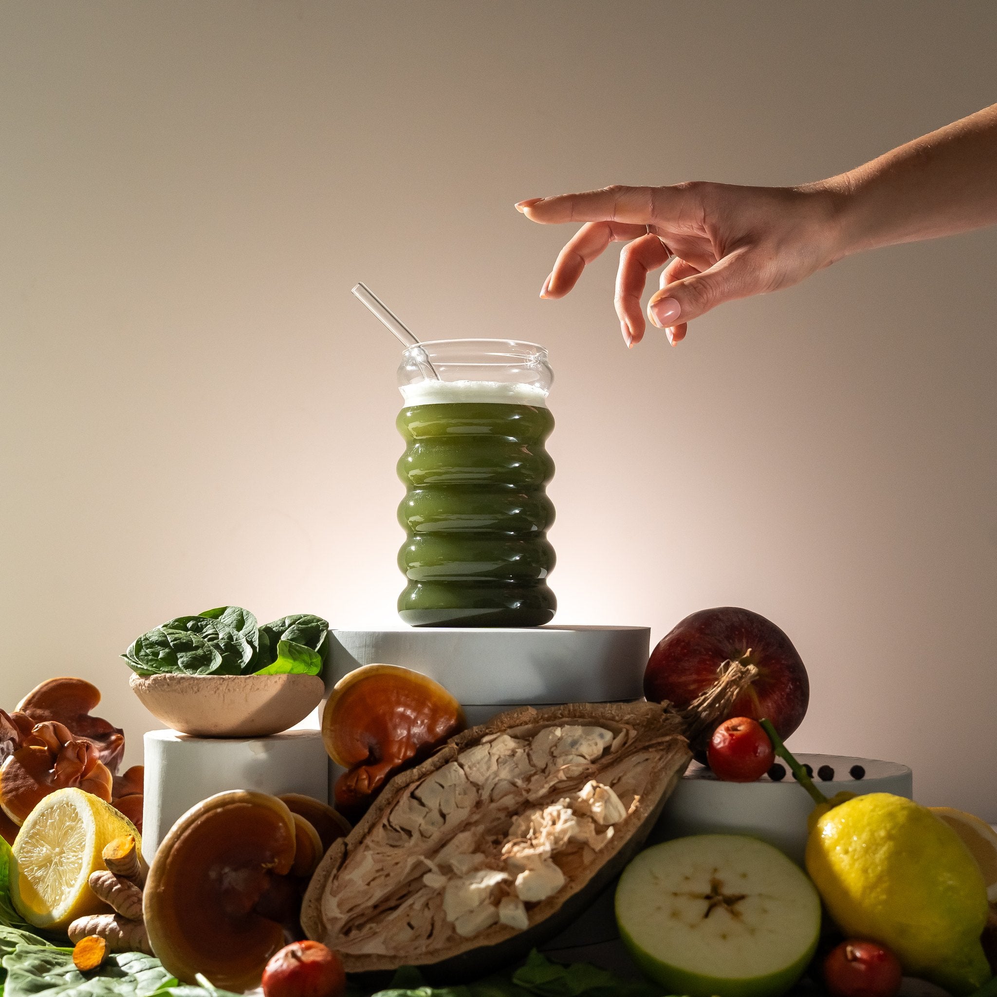 Hand reaching for a glass of Releaf Super Greens above fresh ingredients