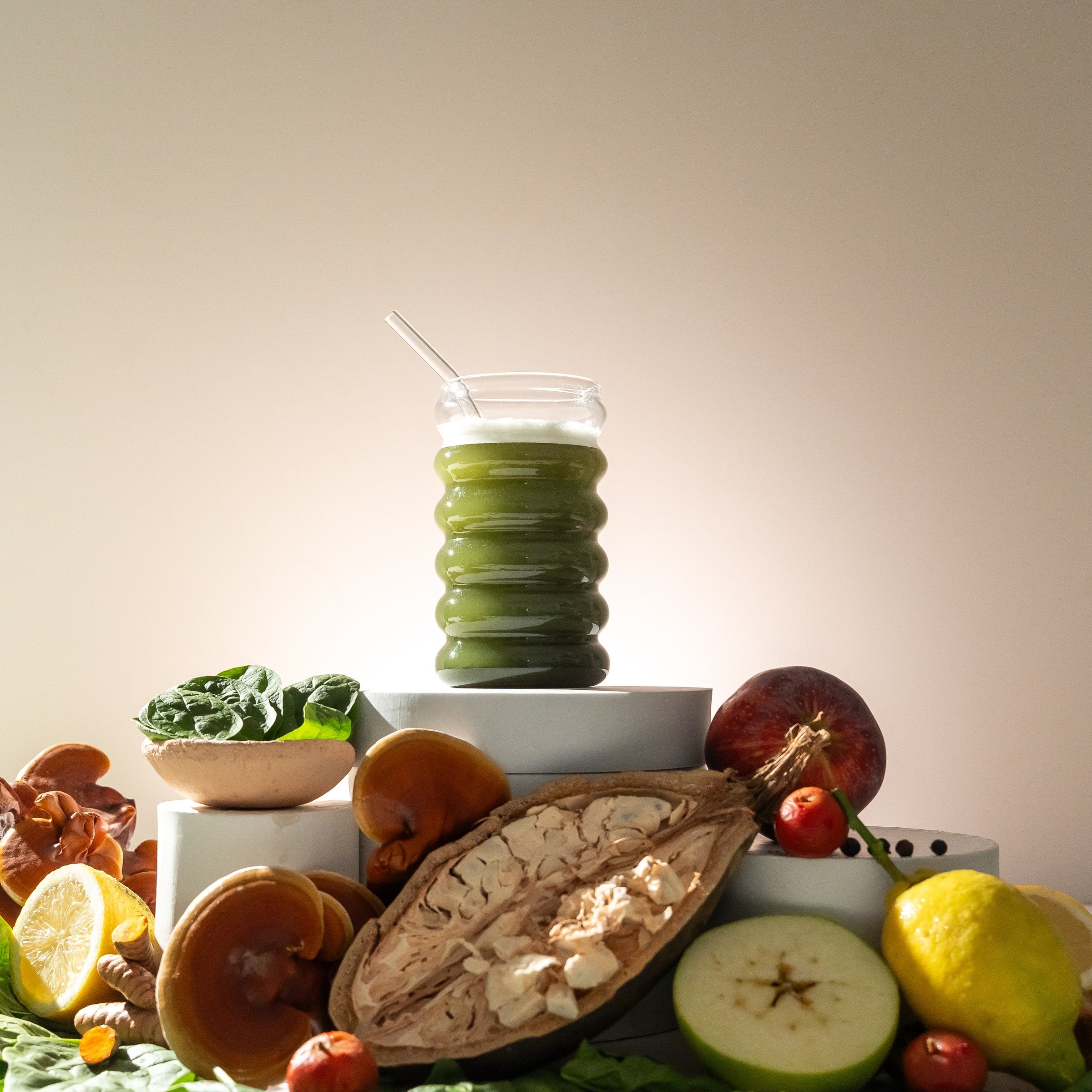 Glass of Releaf Super Greens on a pedestal above fresh organic ingredients