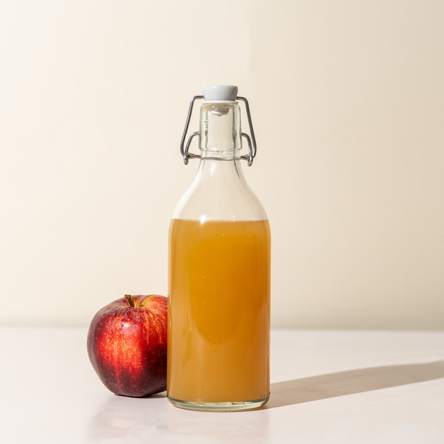 Apple cider vinegar bottle with a fresh red apple