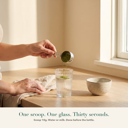 A 10g scoop of Releaf greens being tipped into a glass of water. One scoop, one glass, thirty seconds