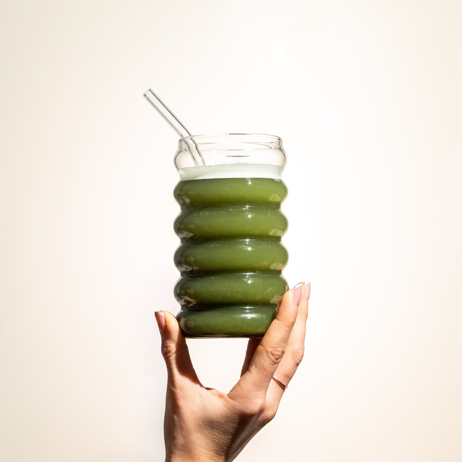 Hand holding a glass of freshly mixed Releaf Super Greens