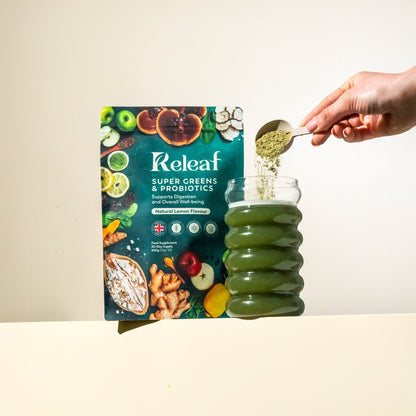 Releaf Super Greens &amp; Probiotics pouch with a scoop of greens powder being poured into a glass