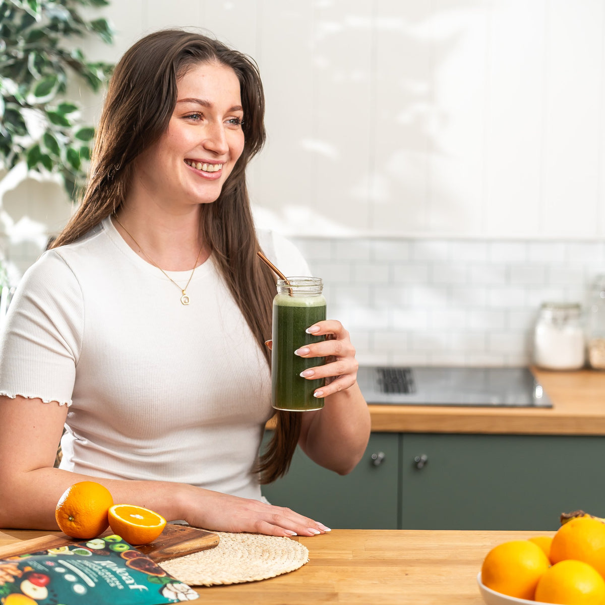Smiling woman holding a glass of lemon-flavoured Releaf greens